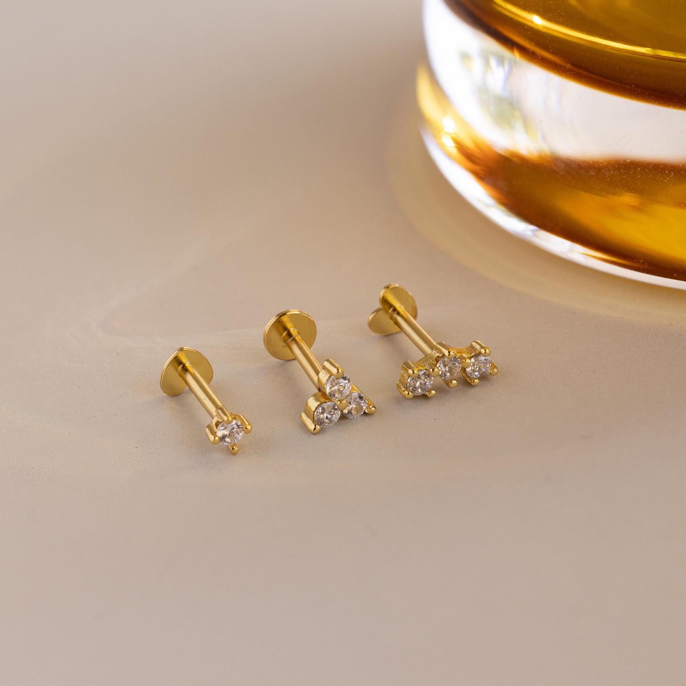 Flat lay of 3 dainty gold CZ Diamond Constellation Flat Back Stud Earrings, 2 earrings have heart shaped flat backs and 1 has classic circle back
