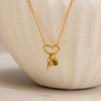 The Heart Carabiner Set in 18K Gold features a heart-shaped pendant, heart carabiner, and small P and circular charms—an elegant necklace to enhance any jewelry collection.