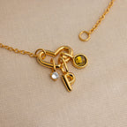 The Heart Carabiner Set in 18K Gold features a heart-shaped clasp, letter P, clear gem, and yellow gemstone charm—ideal for mixing with your jewelry or as a unique charm bracelet connector.