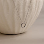 Cable Circle Charm Necklace shown on a textured, off-white ceramic background—a stylish statement piece suitable for any occasion.