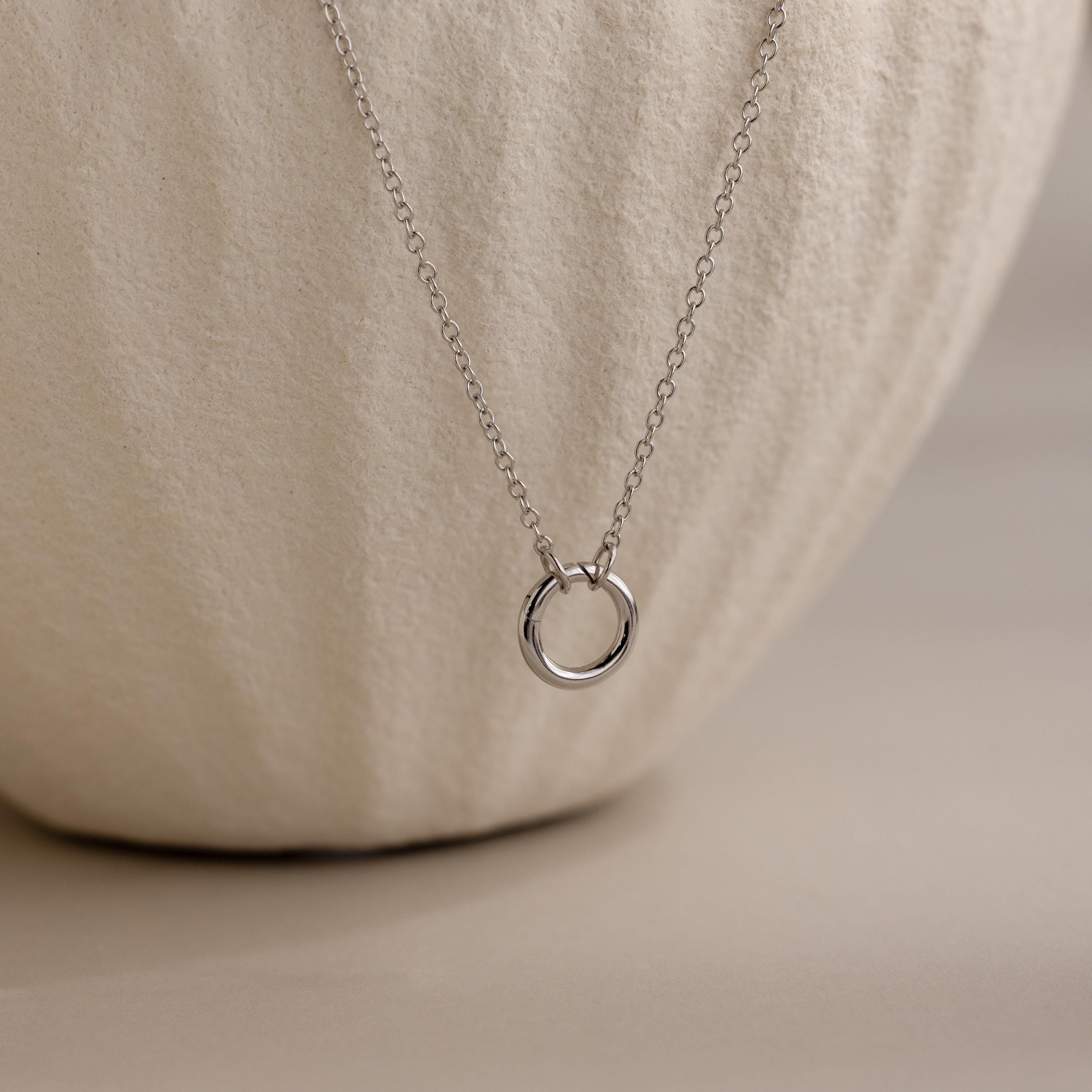 Cable Circle Charm Necklace shown on a textured, off-white ceramic background—a stylish statement piece suitable for any occasion.