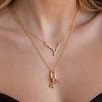 A woman’s layered gold necklaces—featuring letter and gem pendants—stylishly match her stacked bracelets, all highlighted by the Multipurpose Charm Hoop Clasp Set in 18K Gold for enhanced versatility.