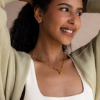 Smiling woman wears the Paperclip Clasp Necklace and hoop earrings, styled with a cream top and light cardigan.