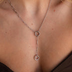 Close-up of a silver Rolo Lariat Paperclip Clasp Necklace with two interlocking circles, worn on a woman's neck.