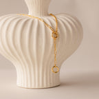 A Rolo Lariat Paperclip Clasp Necklace draped over a white textured ceramic vase with vertical grooves.