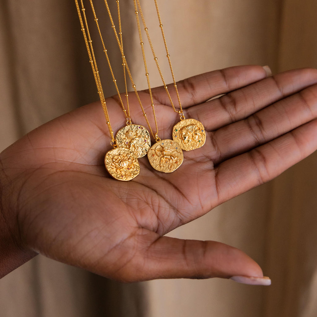 Model showing 4 Gold Zodiac Coin Necklaces with small CZ gemstones attached to a satellite chain.