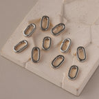 Ten Multipurpose Charm Hoop Clasps in white gold, displayed on a textured beige geometric surface—ideal for bracelet stacking or as unique connectors for your custom jewelry creations.