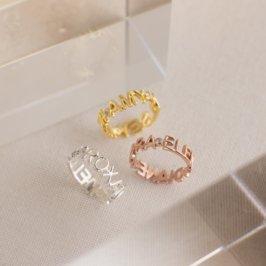 The Multiple Name Eternity Ring features three metallic bands in gold, silver, and rose gold with cut-out capital letters—an elegant and meaningful gift for mom.