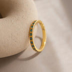 An Art Deco Blue Zircon Eternity Ring featuring blue zircon stones set in a row, displayed on a textured beige surface.