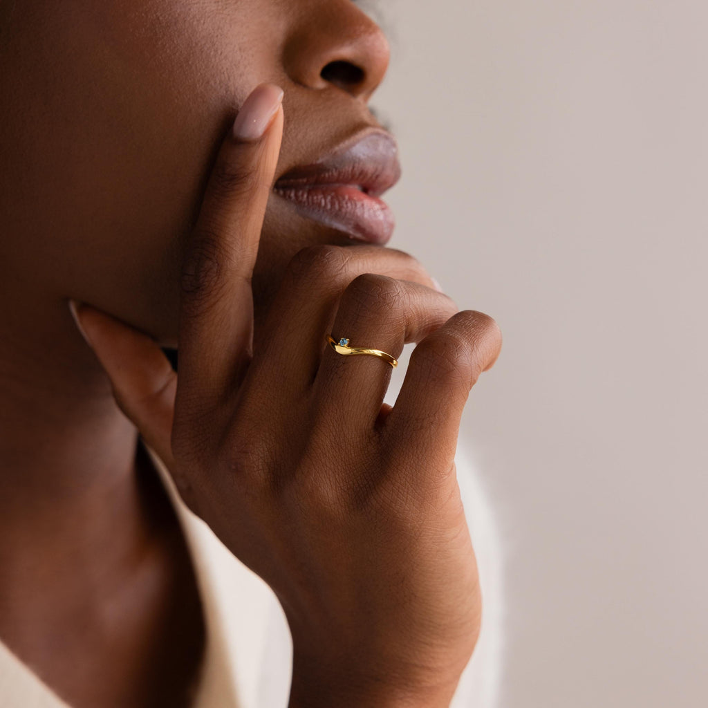 A close-up of a woman’s hand adorned with the delicate Birthstone Drop Curve Ring.