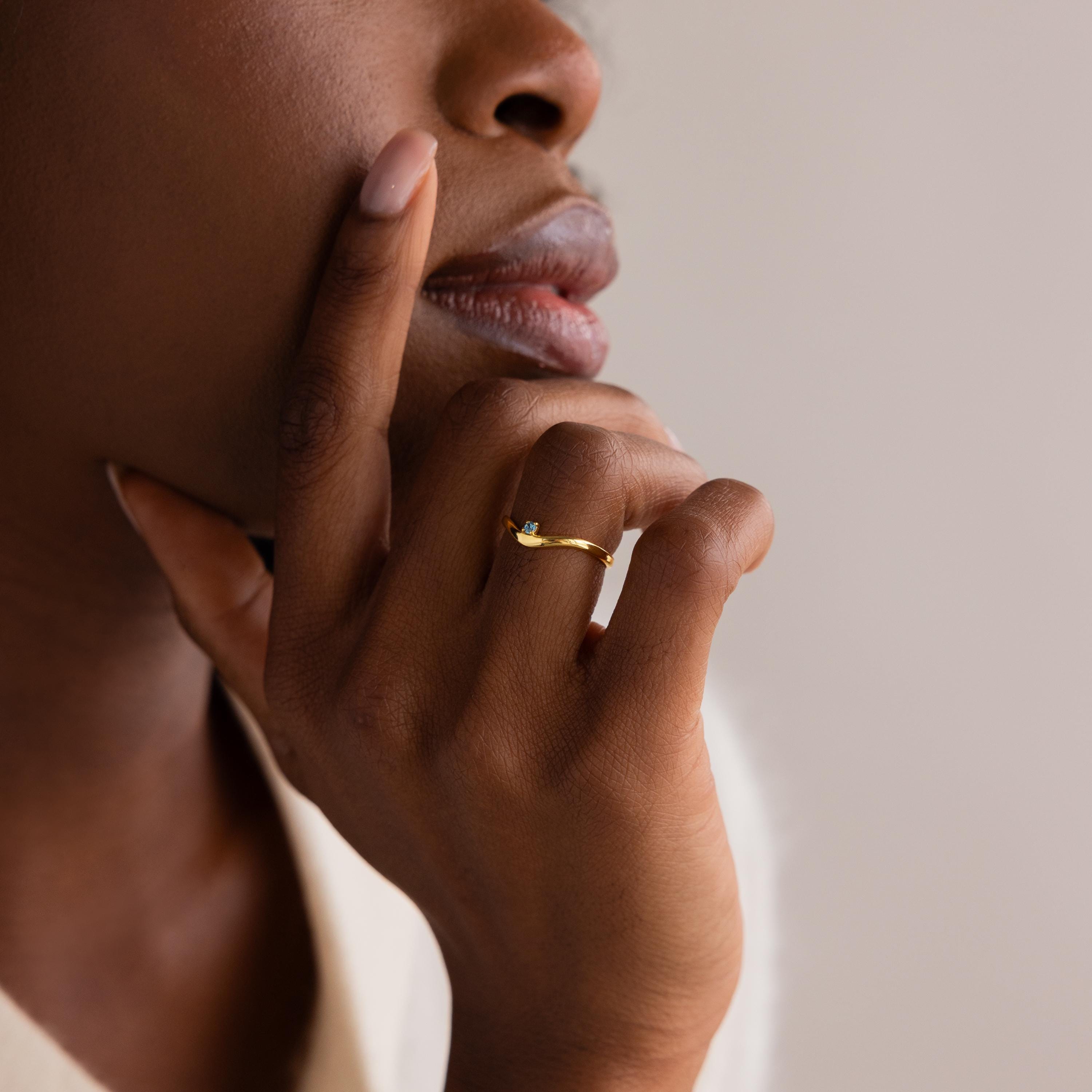 A close-up of a woman’s hand adorned with the delicate Birthstone Drop Curve Ring.