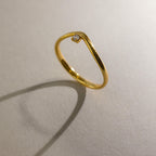 The Onyx Drop Curve Ring casts a shadow on a light, textured surface.