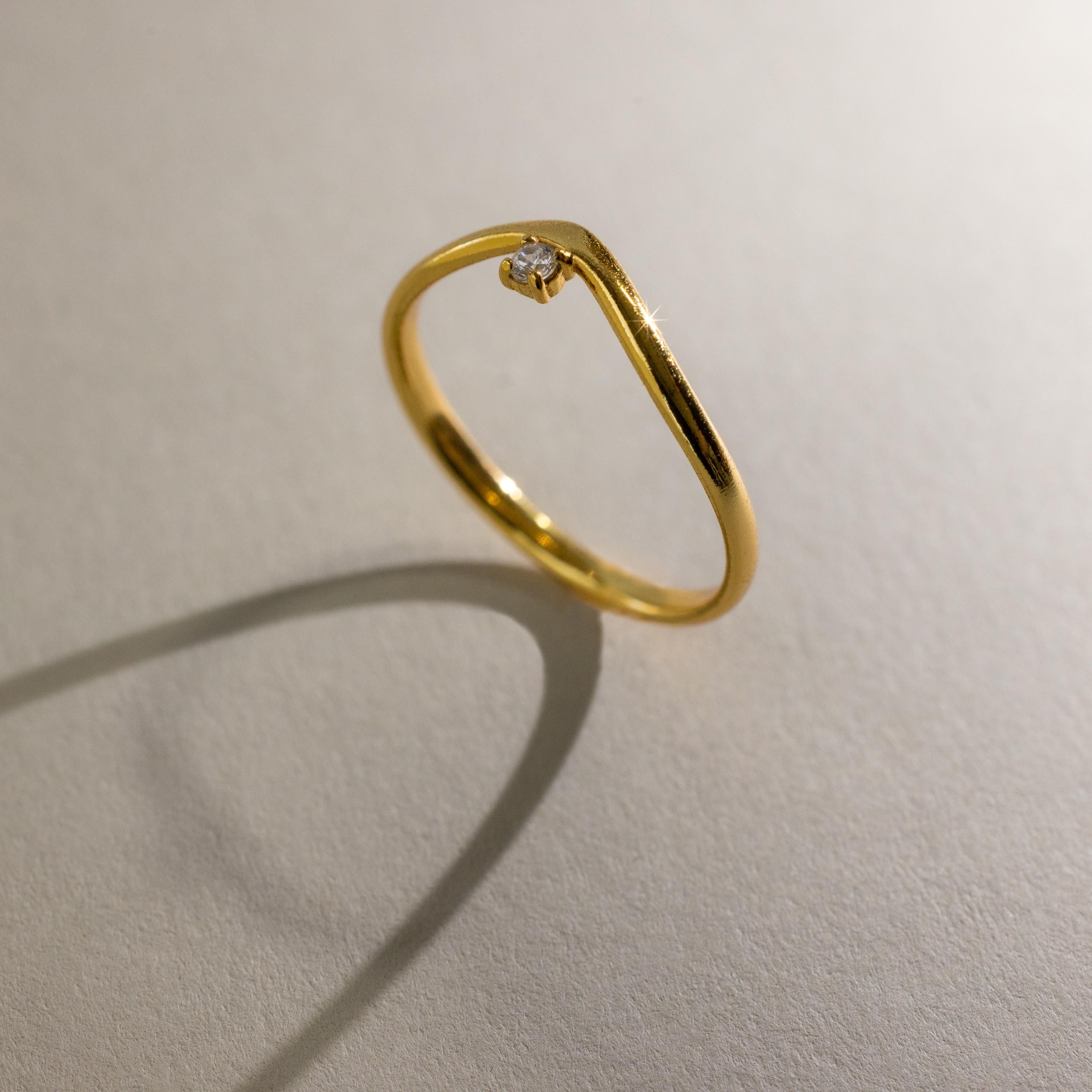 The Onyx Drop Curve Ring casts a shadow on a light, textured surface.
