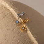 Two hand-and-star pendants—one in silver, one in gold—are styled side-by-side on a textured neutral surface.