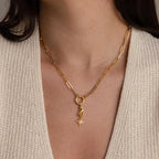 The gold hand and star pendant hangs from a chunky gold paperclip chain necklace worn by a model