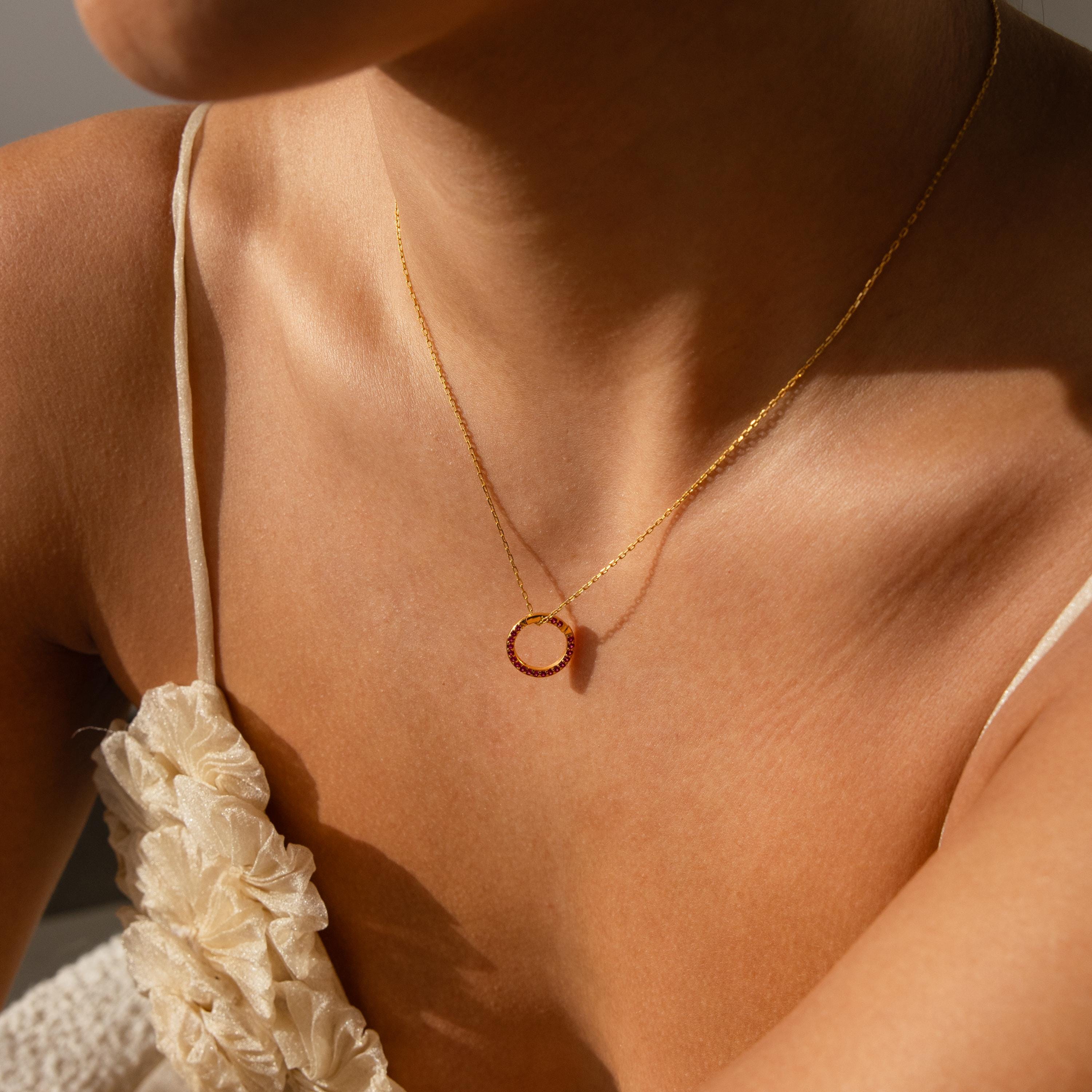 Woman wearing a Pave Garnet Charm Clip and a cream textured spaghetti strap top, sunlight on her skin—showcasing effortless style and jewelry personalization.