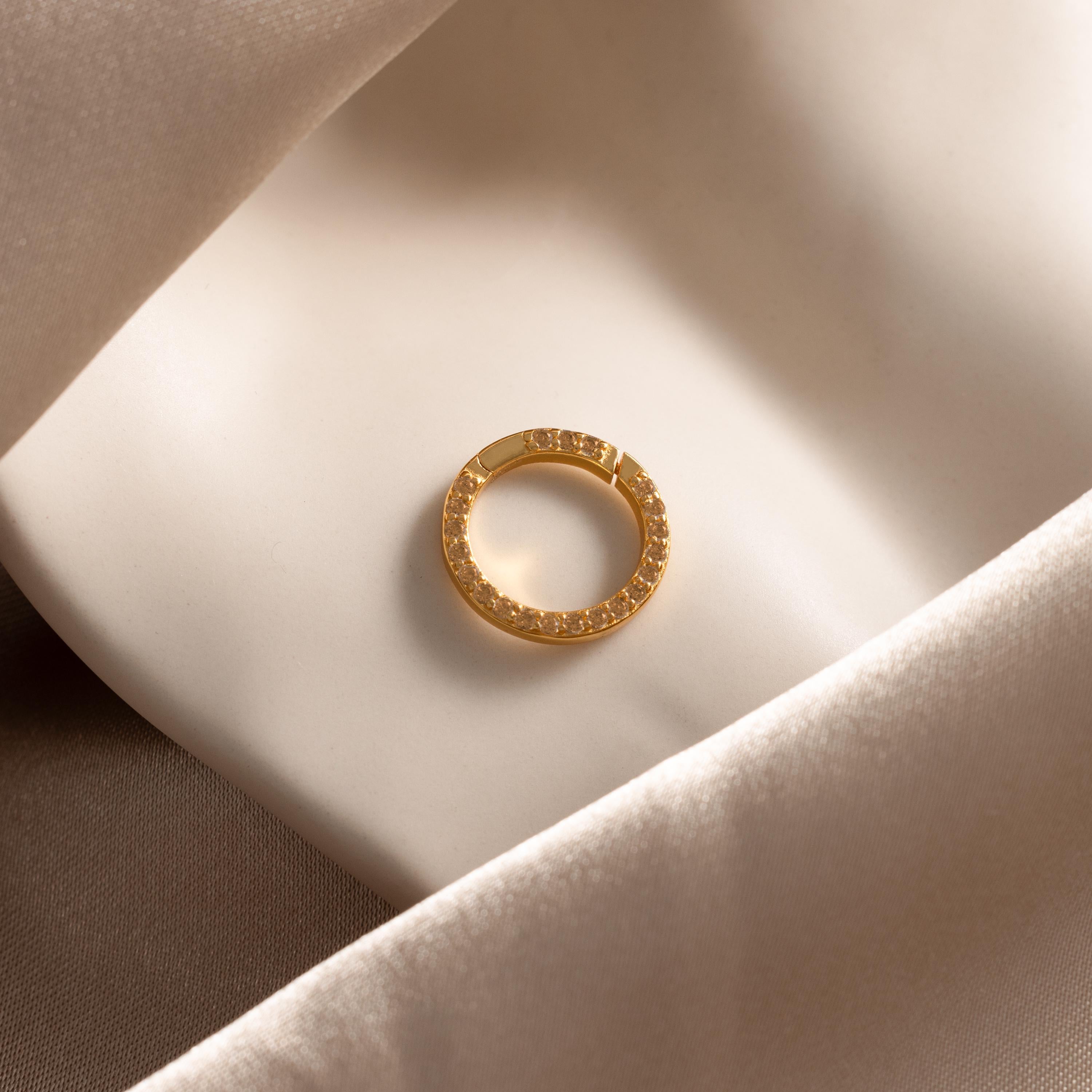 The Pave Topaz Charm Clip, adorned with sparkling gems and displayed on soft cream fabric, is the perfect accent for your personalized jewelry or charm holder.