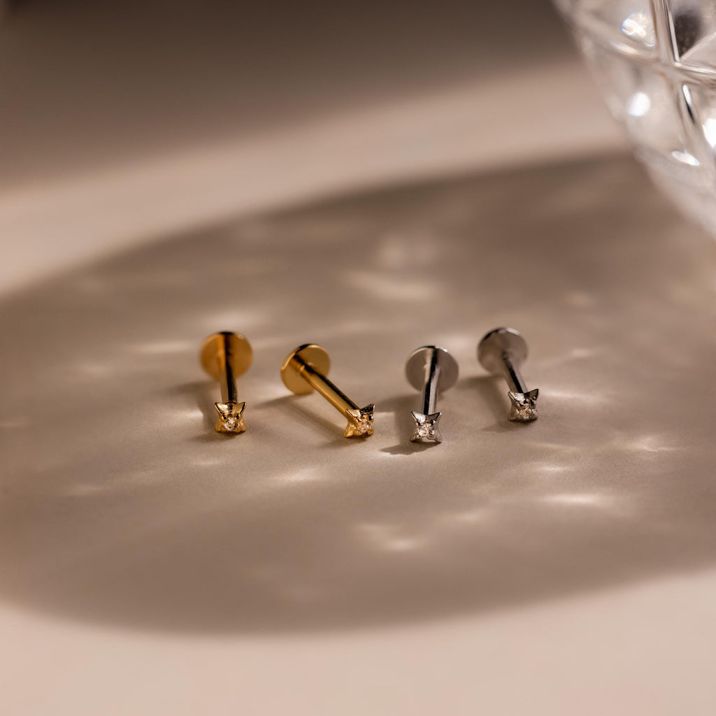 Two pairs of of gold and silver North Star Stud earrings laying side by side