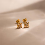 Flat lay of gold Pave North Star Earrings on soft beige surface