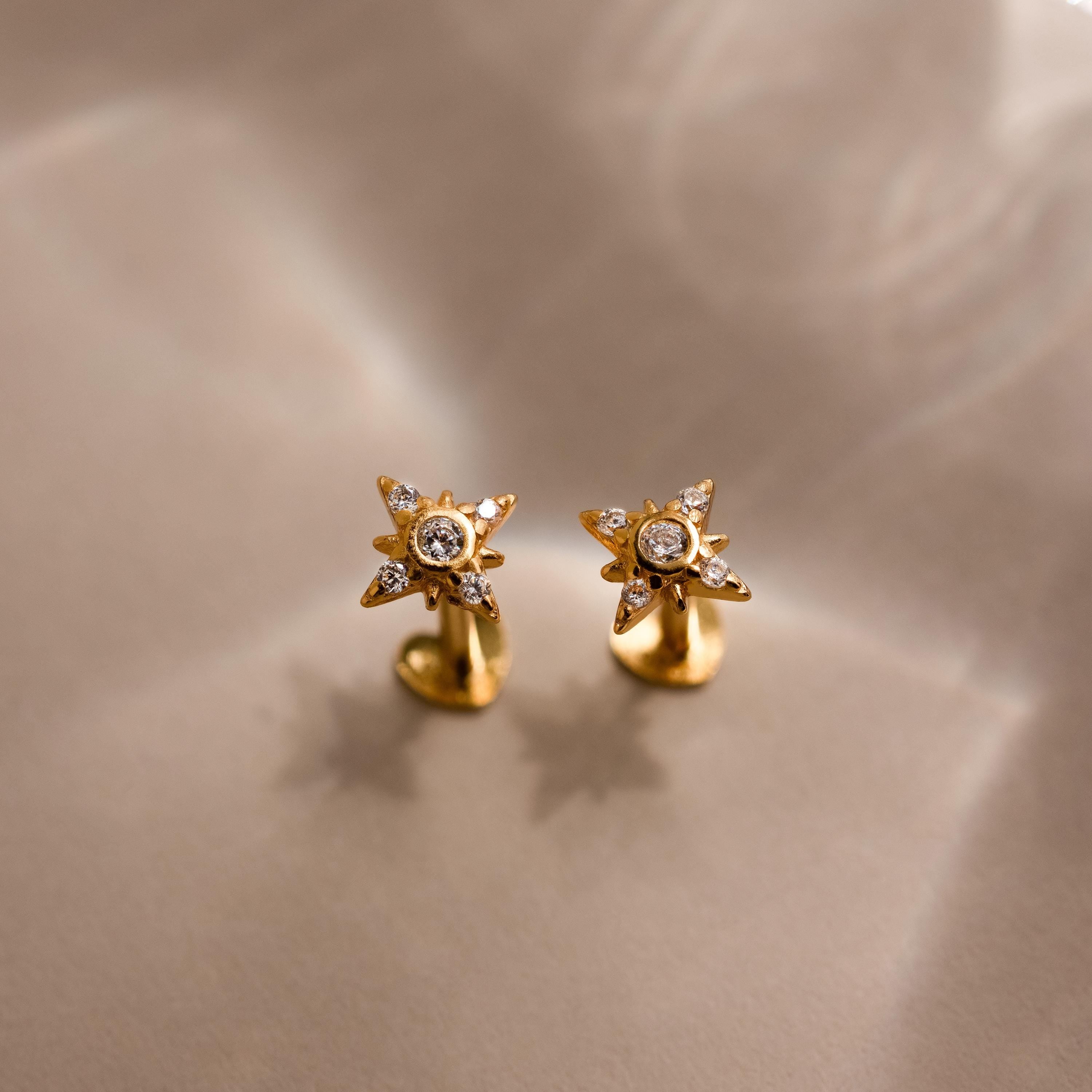 Flat lay of gold Pave North Star Stud Earrings with heart shaped flat backs looking up on a beige surface, highlighting the design of the studs