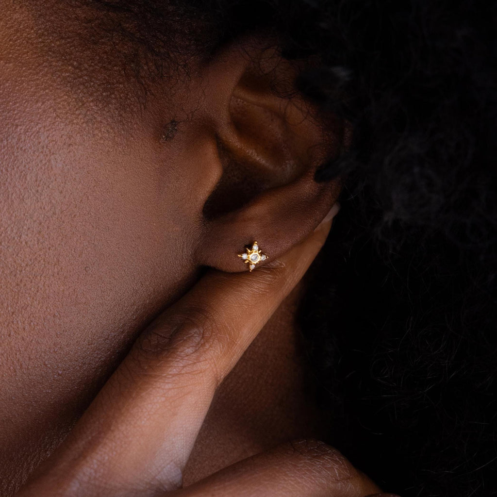 Close up of Pave Diamond North Star Earrings on model's ear. Earrings have a round diamond in the center and other diamond stones arranged in a star shape