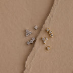Set of 3 silver dainty CZ Diamond Constellation Studs next to set of 3 gold dainty CZ Diamond Constellation Studs displayed on a beige background