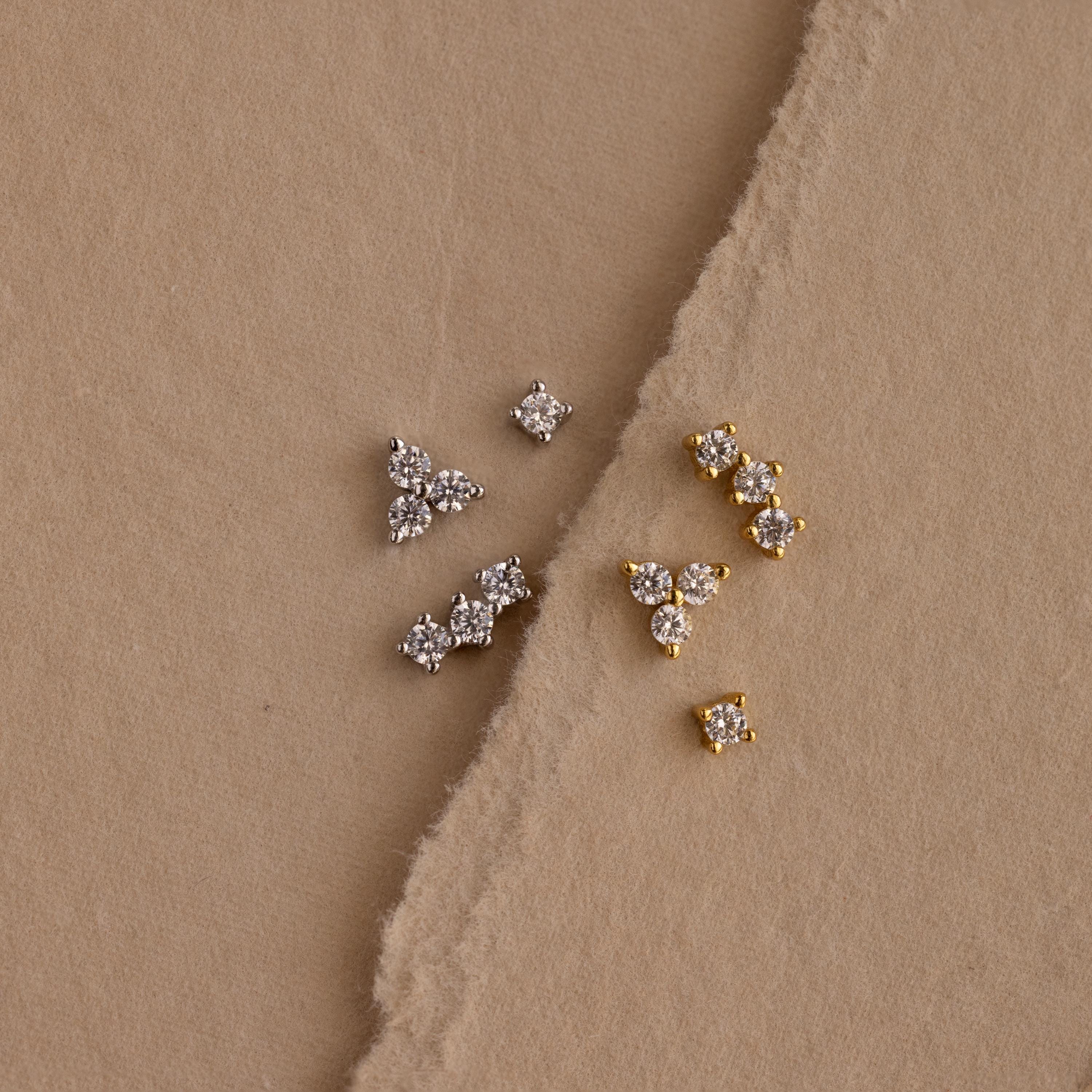 Set of 3 silver dainty CZ Diamond Constellation Studs next to set of 3 gold dainty CZ Diamond Constellation Studs displayed on a beige background