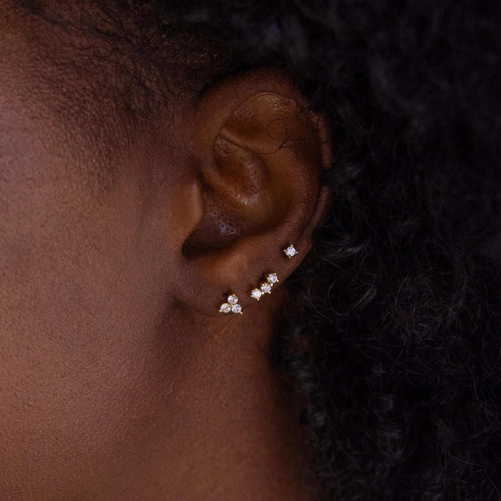 Close up of model wearing an earring stack of 3 dainty gold CZ Diamond Constellation Studs