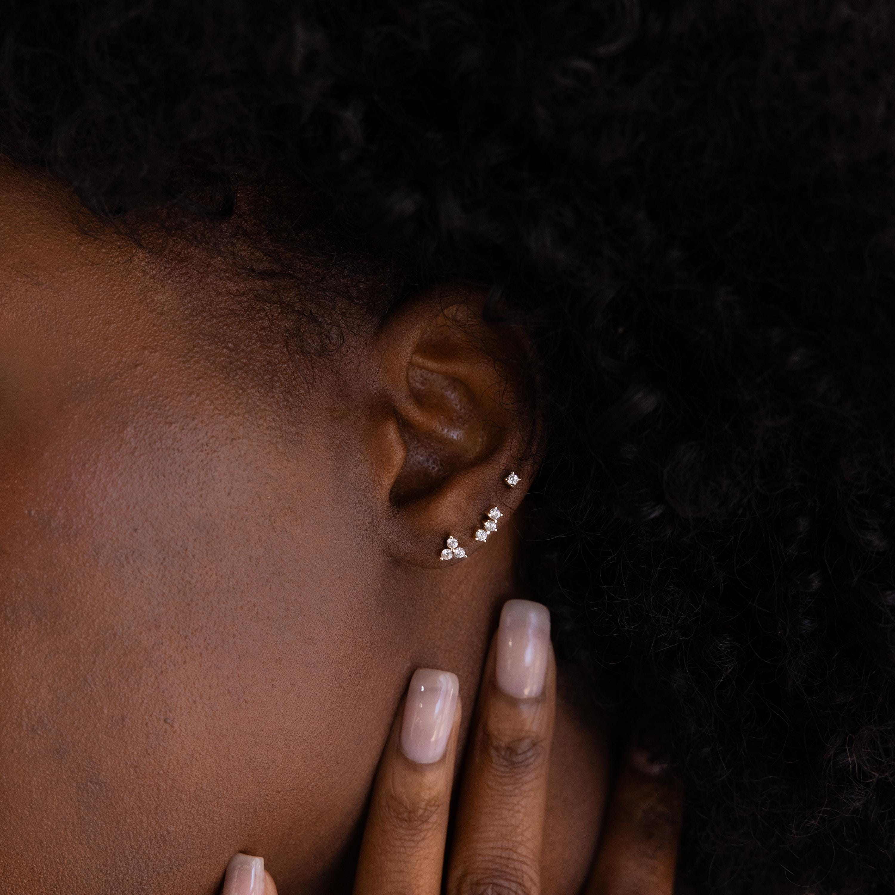 Close up of model wearing an earring stack of 3 dainty mismatched CZ Diamond Constellation Studs