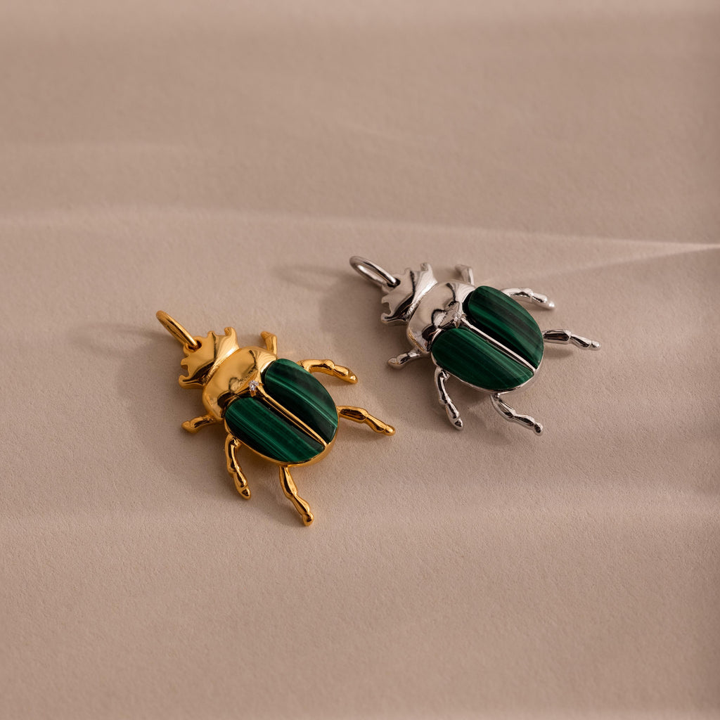 Two beetle charms side by side — one in gold and one in silver