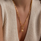 A single Opal Sun Charm is styled on a gold paperclip chain, worn on the chest with a textured knit top
