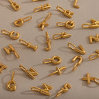 Bubble Letter Charms scattered on a beige surface—perfect for creating your own personalized jewelry collection.