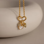 A gold necklace featuring a heart-shaped link holding three charms: the Evil Eye Hand Charm, a mother-of-pearl heart, and a strawberry.
