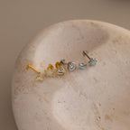 Flat lay of Gold & Silver Opal CZ Diamond Celestial Stud Earring Set with heart shaped flat backing unscrewed, displayed on round stone surface.