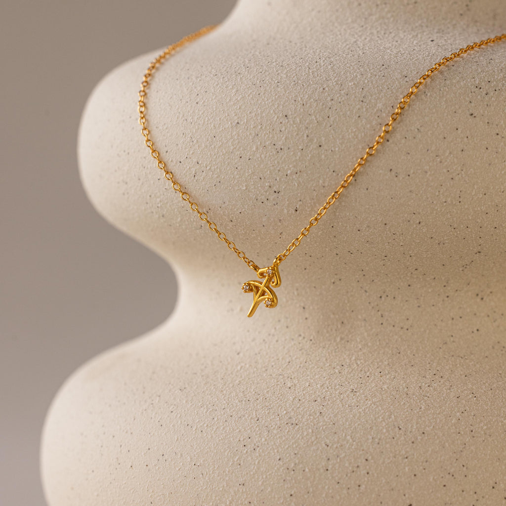 Gold CZ diamond dainty Sagittarius Zodiac Charm Necklace hanging from vase.