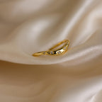 Close up of a gold celestial wave ring laying on a cloth surface