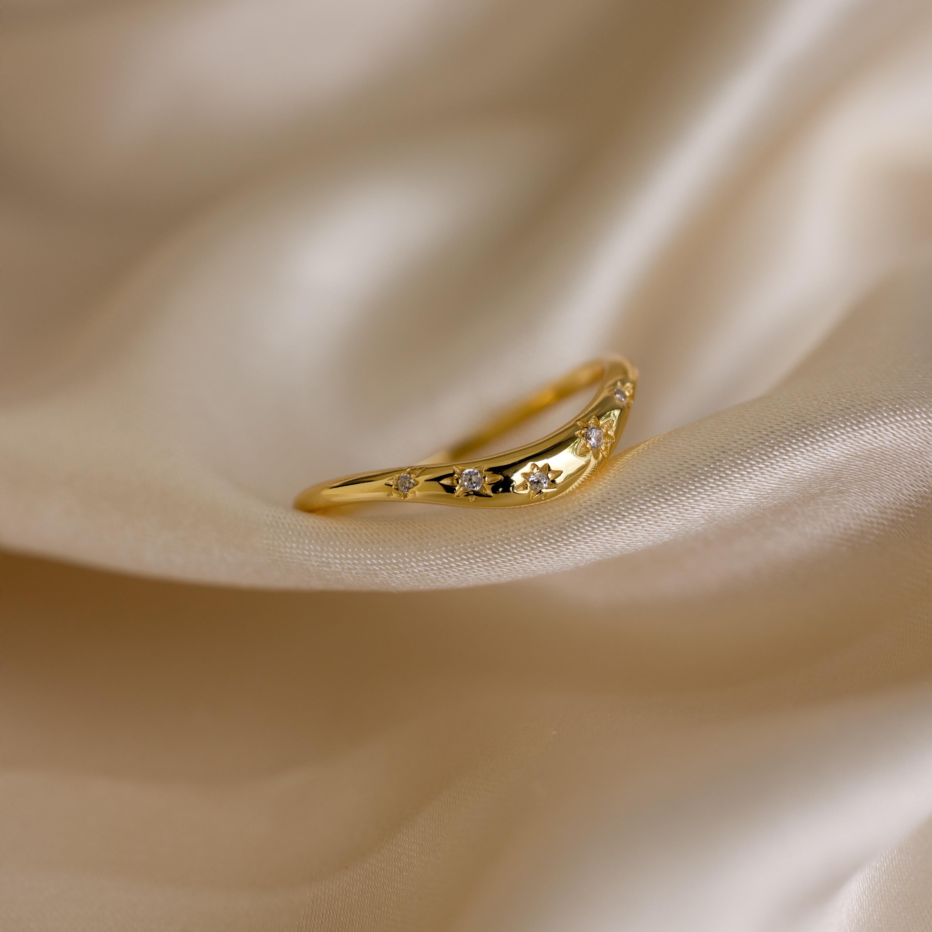 Close up of a gold celestial wave ring laying on a cloth surface
