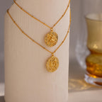 A Pisces and Sagittarius Zodiac Gemstone Coin Necklace hanging on a sculpture