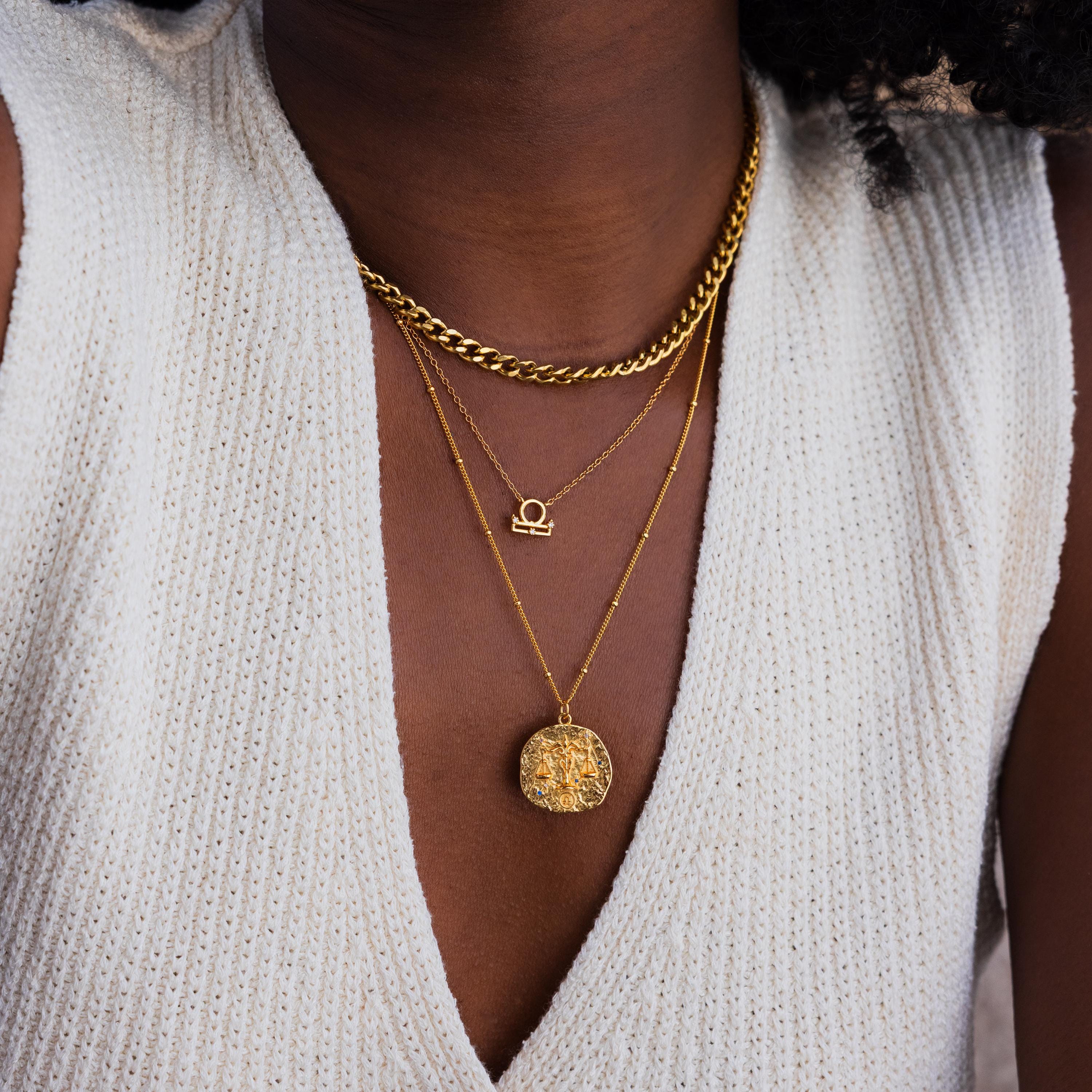 Model wears a gold libra Zodiac Gemstone Coin Necklace, pairing it with a libra symbol necklace and a gold curb chain