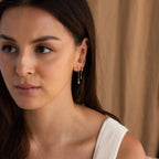 Model wearing Gold star drop chain earrings paired with another star chain stud earring