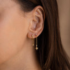 Close up of model wearing Gold star drop chain earrings paired with another star chain stud earring