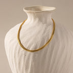 A single Foxtail Chain Necklace in 18K gold draped over a matte white, textured ceramic bust.
