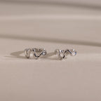 Silver Pavé Viper Huggie Earrings placed on a neutral-toned background