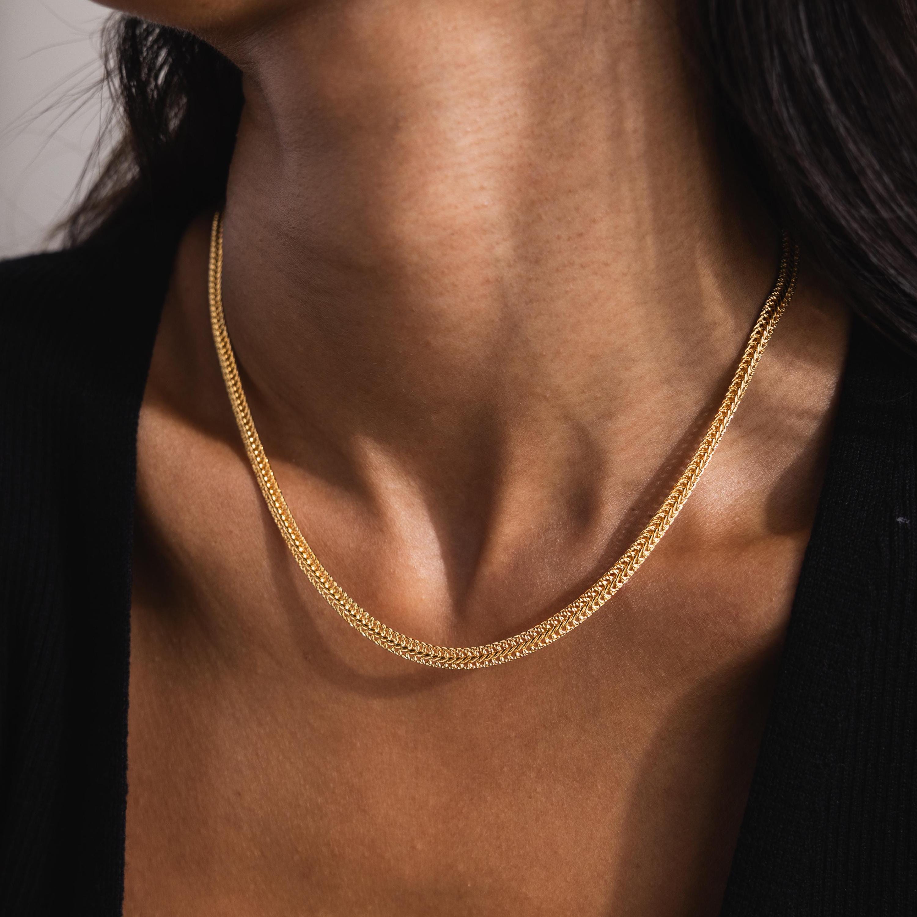 Woman wearing the Thick Mesh Chain Necklace in gold. The textured, wide mesh design features an intricate woven pattern, with a half curb chain design on top and a reversed curb chain side on the bottom, divided by a twisted border in the middle