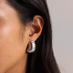 Silver version of the chunky ribbed earring worn close to the ear