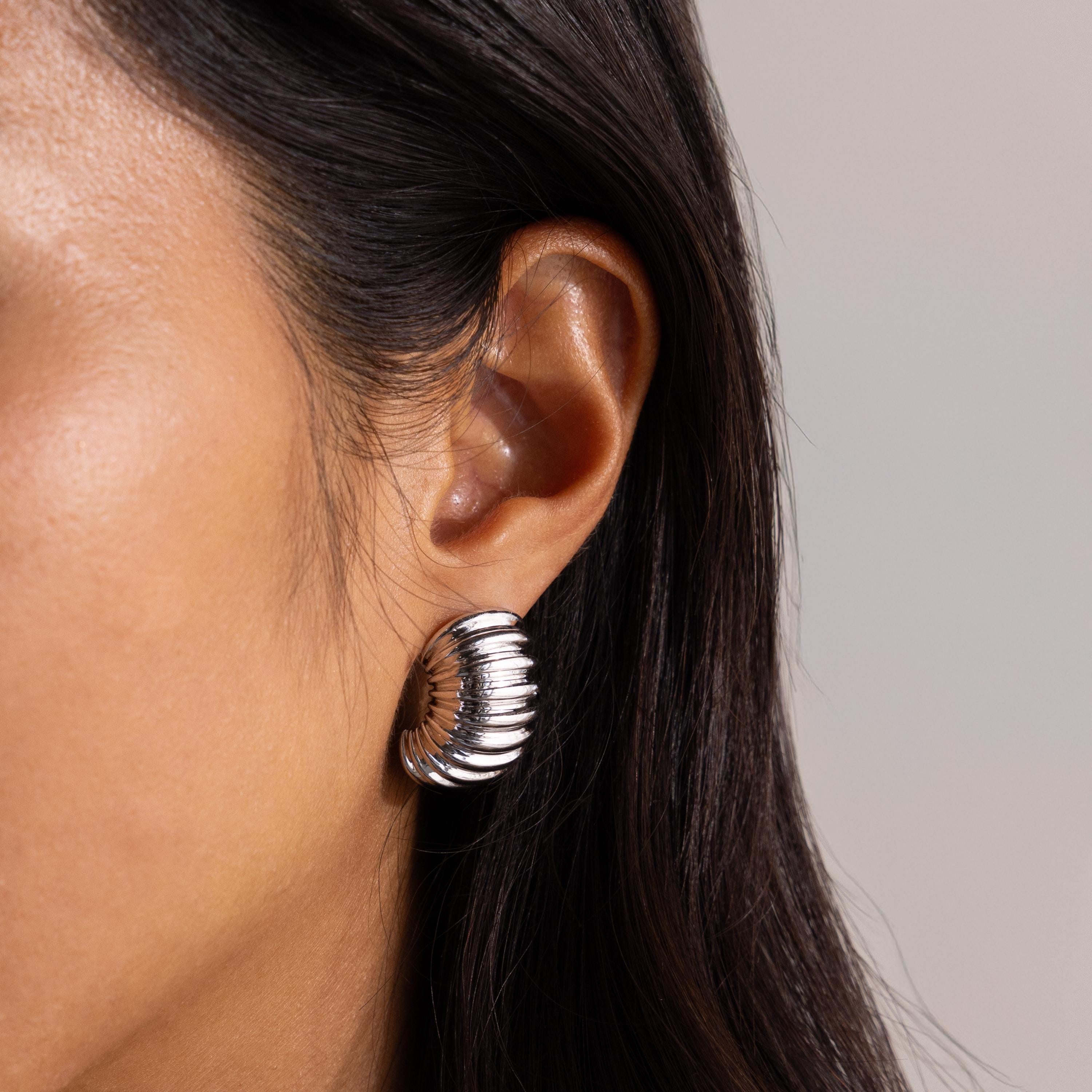 Silver version of the chunky ribbed earring worn close to the ear