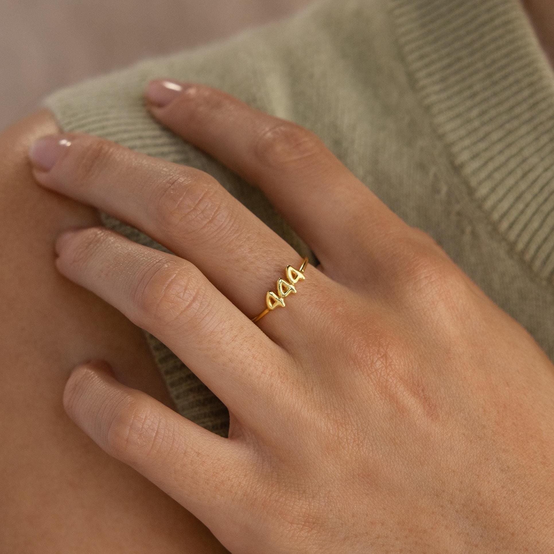 Close up of a hand wearing a gold Bubble Numbers Ring with 1994 in bold, rounded numerals. The ring has a smooth and shiny finish.