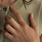 A silver Bubble Numbers Ring with “2006” is worn on the index finger against a sage green sweater.