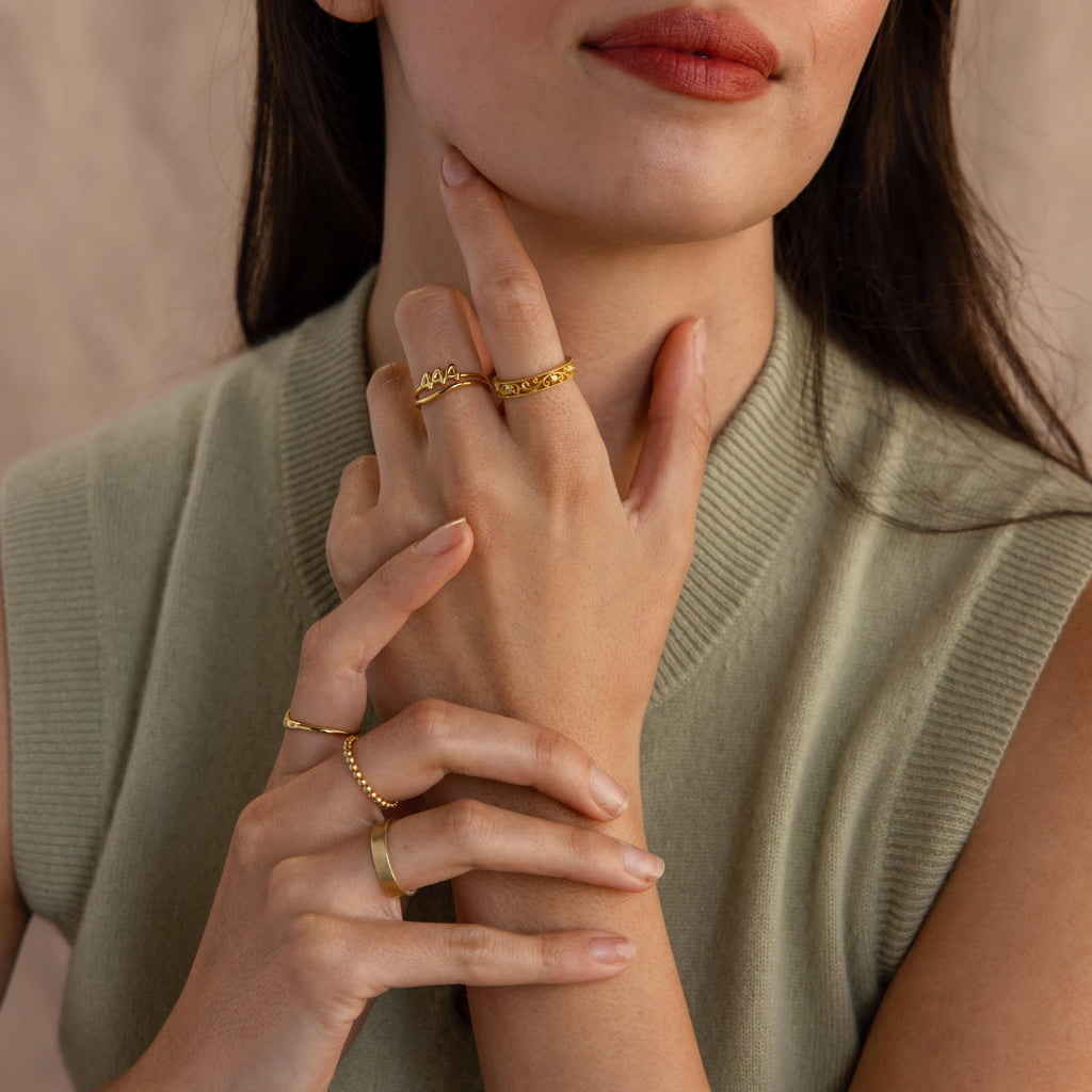 The model wears multiple golden rings in a stylish look, including a “1994” Bubble Numbers Ring on her middle finger.