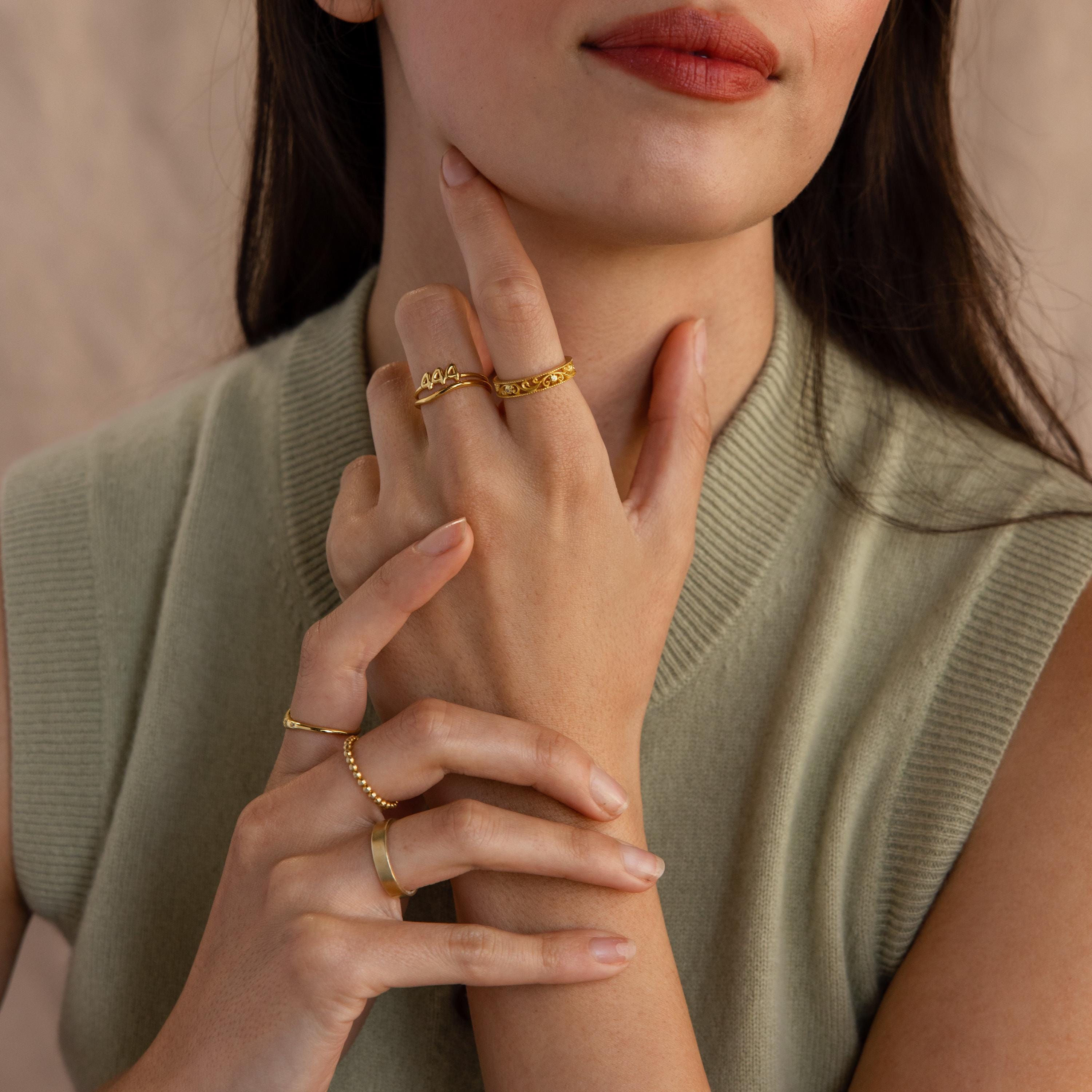 The model wears multiple golden rings in a stylish look, including a “1994” Bubble Numbers Ring on her middle finger.